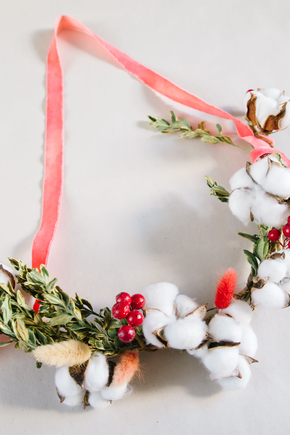 Adding red berries to diy Christmas wreath.
